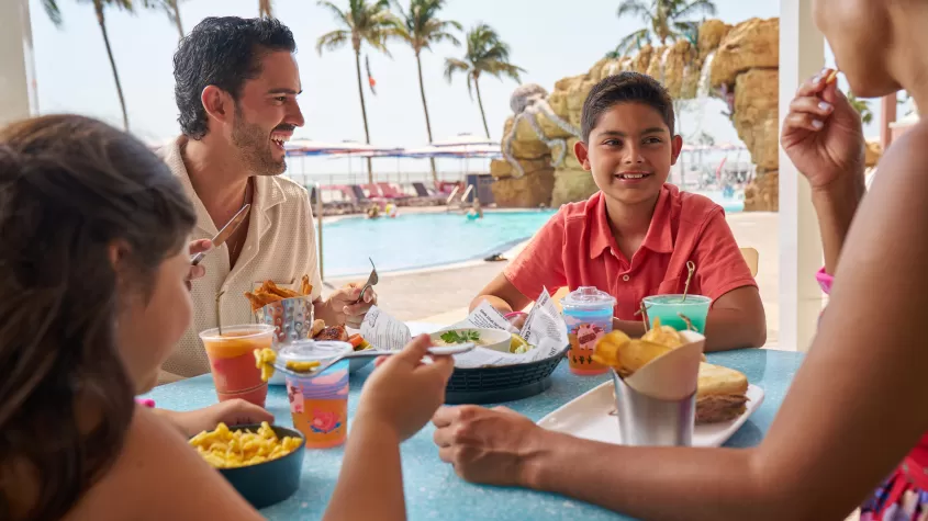 Family enjoying lunch with pool in background