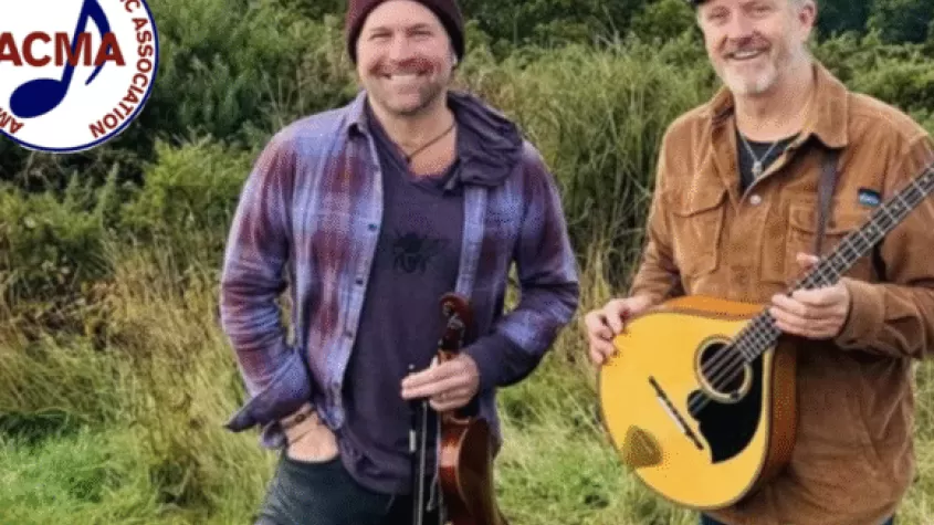 Two men standing, one with a mandolin and the other with a fiddle.  ACMA logo in corner.